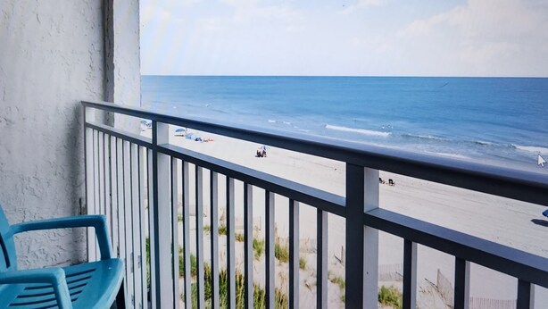 A balcony with a view of the beach, a railing, and two blue chairs. - Oceanfront Efficiency T507 (Myrtle Beach)