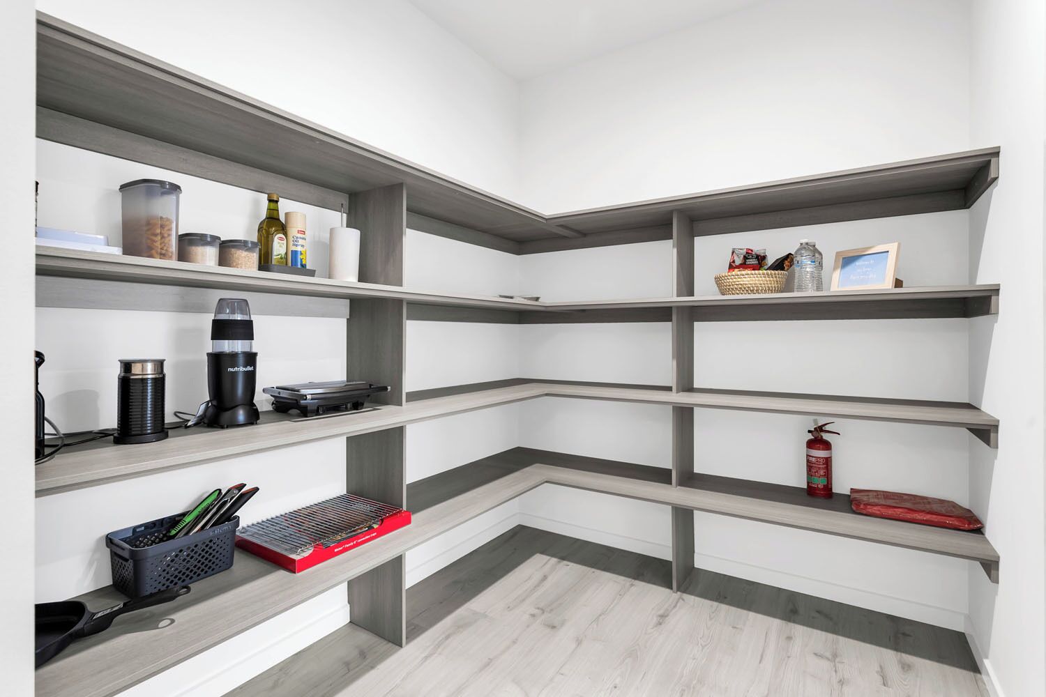 A modern kitchen with built-in shelves, a coffee machine, and a fire extinguisher.