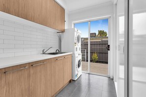 A modern kitchen with wooden cabinets, a white countertop, and a built-in washing machine.