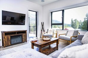 Ein modernes Wohnzimmer mit Kamin, einer Couch, einem Couchtisch und einem an der Wand befestigten Fernseher.