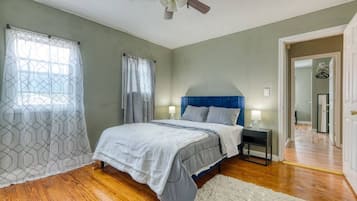 Una camera da letto con un letto, comodini, una ventola a soffitto e vista su un corridoio.