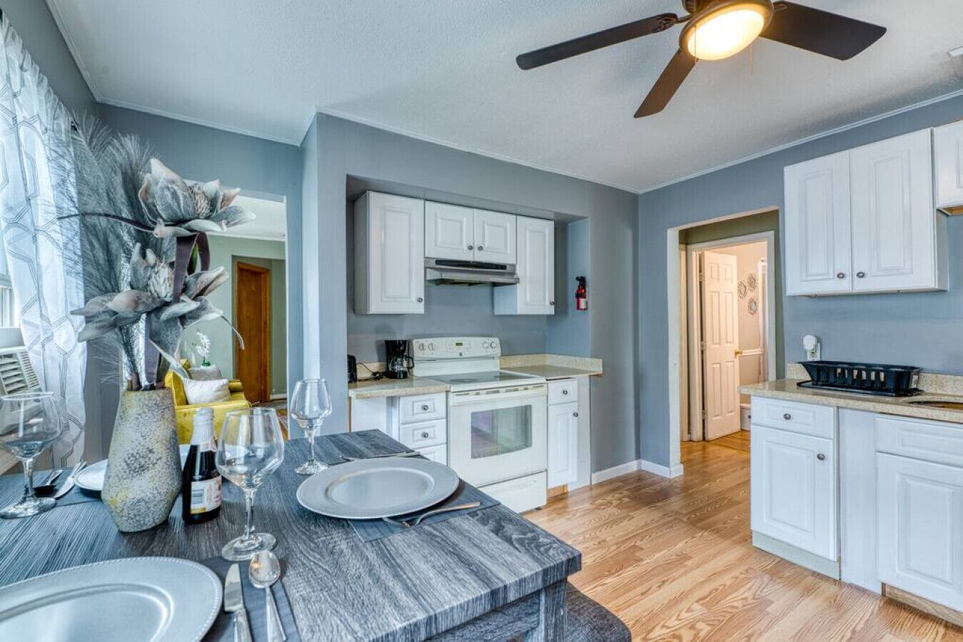 A modern kitchen with white cabinets, a granite countertop, and a ceiling fan.