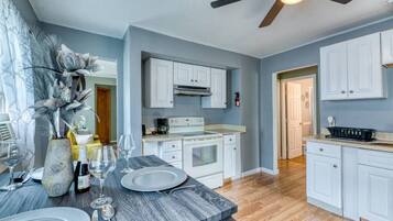 A modern kitchen with white cabinets, a granite countertop, and a ceiling fan.