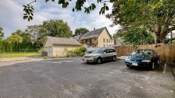 Una strada privata con due auto parcheggiate, una casa e un albero grande.