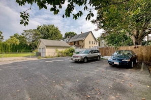 A residential driveway with two parked cars, a house, and a large tree.