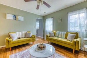 A living room with two yellow sofas, a marble coffee table, and a ceiling fan. - Humble home with free breakfast (Chicopee)