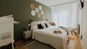 A bedroom with a bed, a nightstand, a dresser, a radiator, and a wall with circular decorations.