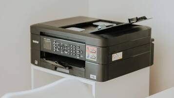 Een zwarte printer op een wit bureau.