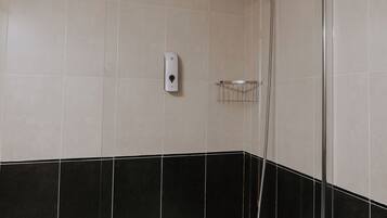 A bathroom with a bathtub, a shower, and a hand dryer on the wall.
