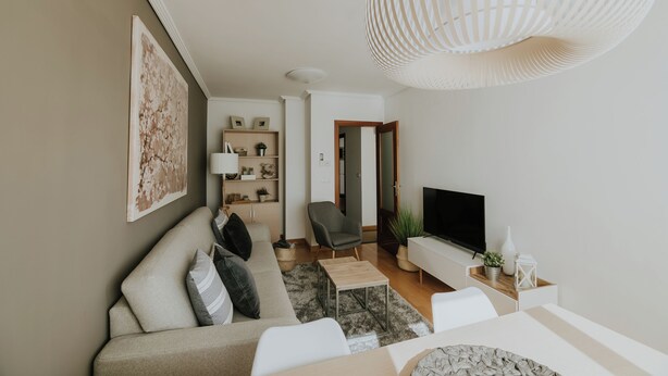 A modern living room with a sofa, TV, and decorative items.