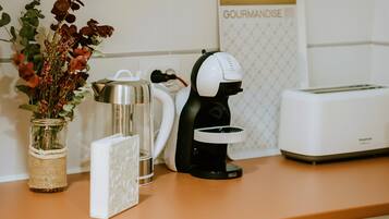 A kitchen counter with a coffee maker, a toaster, and a decorative vase with flowers.