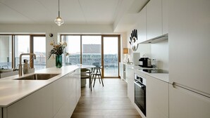 Et moderne køkken med en central ø, store vinduer og udsigt over bybilledet.