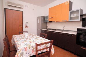 A compact kitchen with a dining area, featuring a refrigerator, stove, sink, and cabinets. - Residence Costa Tirrena (Torrenova)