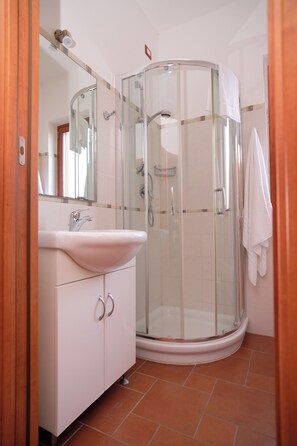 A bathroom with a glass-enclosed shower, a white sink, and a mirror above it. - Residence Costa Tirrena (Torrenova)