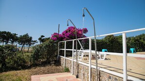 Eine Steinsäule mit Metallgeländer, einem hängenden Blumenarrangement und Sitzgelegenheiten im Freien.