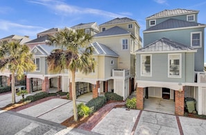 A row of townhouses with a covered patio area, brick foundations, and a clear sky.