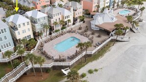 Ein Resort mit mehreren Gebäuden, einem zentralen Poolbereich und einem Strand.