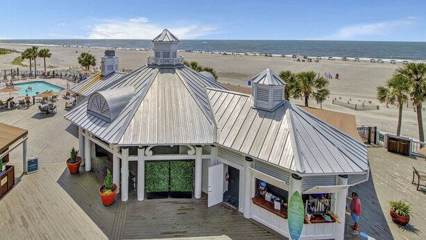 Ein Gebäude direkt am Strand mit Pool, Kiosk und Blick auf den Strand und den Ozean.