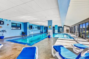 Un espace piscine comprenant deux piscines, des murs bleus et des chaises longues.