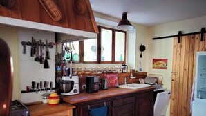 A kitchen with wooden cabinets, a stove, a coffee maker, and various kitchen utensils. - Savoie, St François Longchamp, Très Grand Appartement de 180 m2, 12 Couchages (Saint-François-Longchamp)