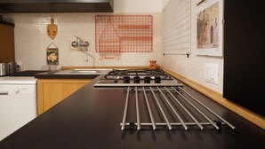 A kitchen with a gas stove, wooden cabinets, and a tiled backsplash.