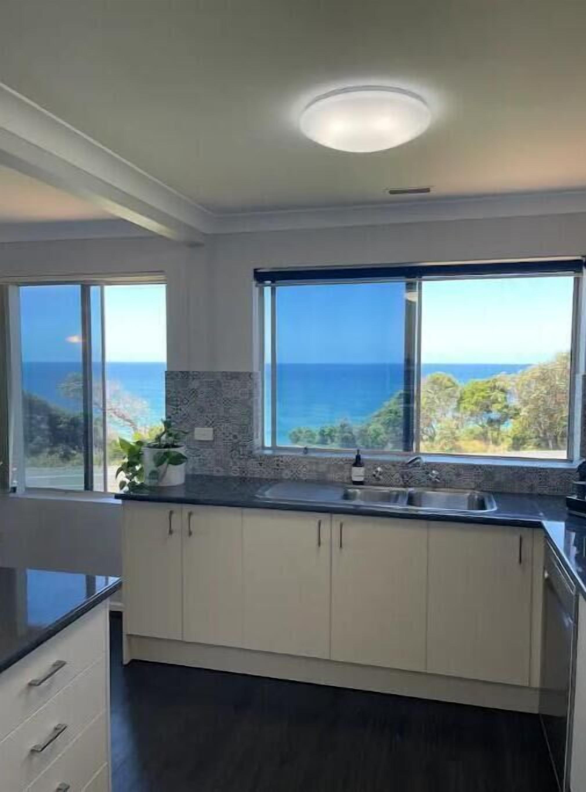 A modern kitchen with large windows offering ocean views.