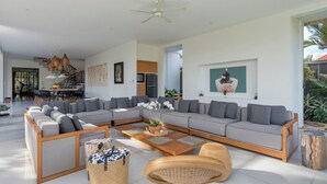 Een ruime woonkamer met een grote hoekbank, een salontafel en een eethoek met stoelen en een tafel.