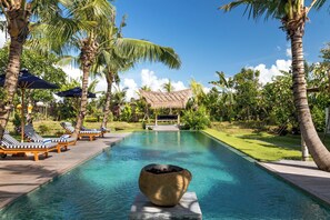 A pool area with lounge chairs and a thatched-roof structure. - Luxury and TOP Location in Canggu! (Canggu)