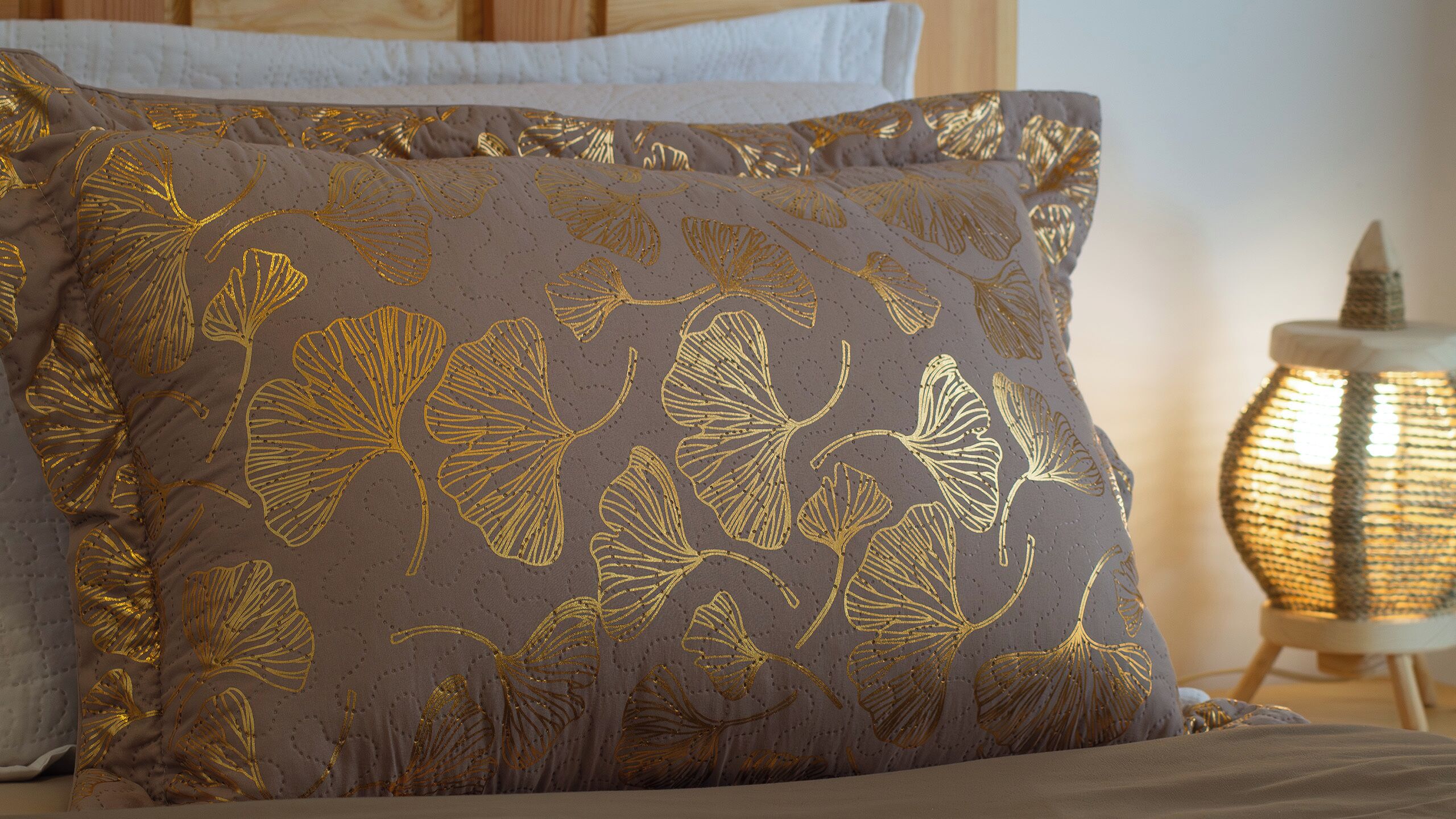 Una cama con un almohadón estampado con hojas.