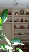 Una stanza con una ventola a soffitto, scaffali con piatti decorativi e una pianta grande.