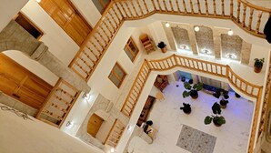 Un interior de varios niveles con una escalera de madera, suelo de mármol y azulejos de pared con diseños.