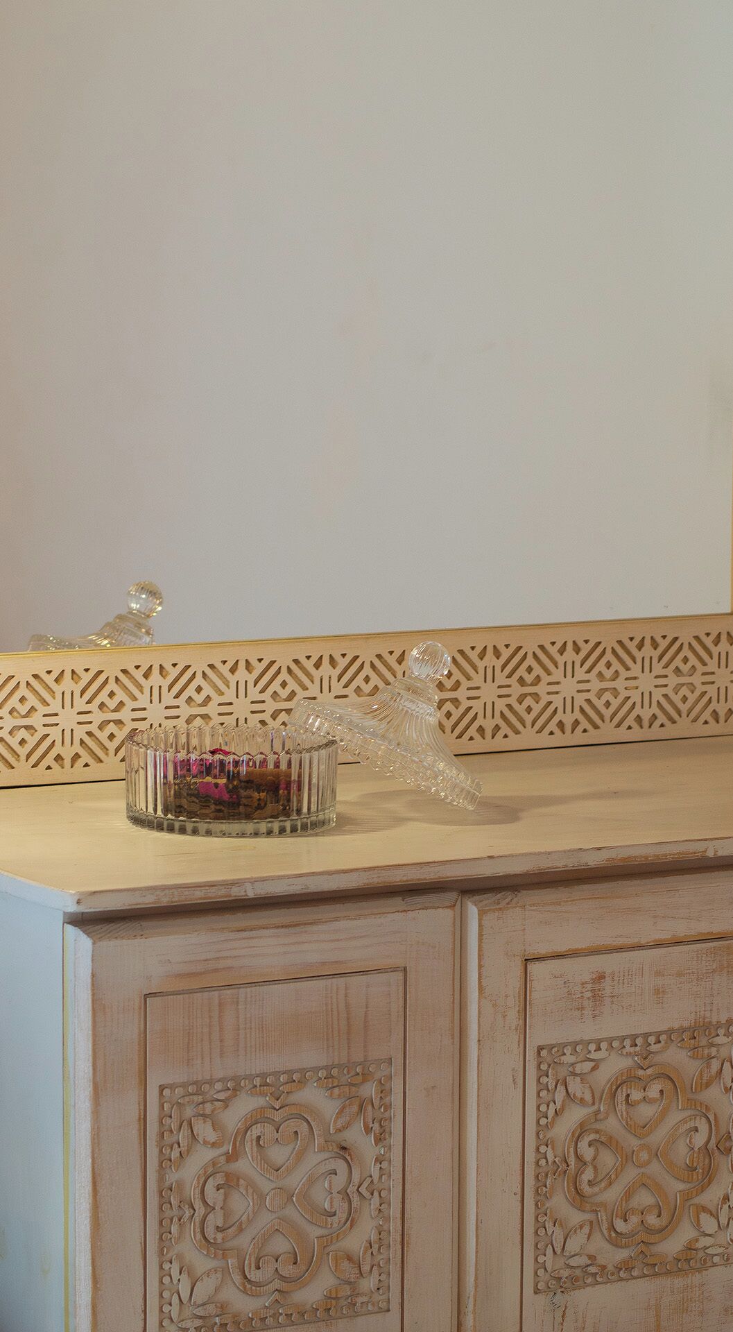 A kitchen with a decorative backsplash, a glass container with a lid, and a wooden cabinet with carved details.