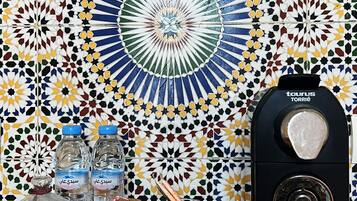 A tiled wall with a geometric pattern, a water dispenser, and various glass containers on a wooden surface.