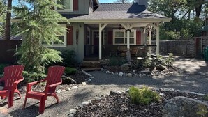 A two-story house with a front porch, a small garden, and two red Adirondack chairs. - Adventure Awaits! - Twain Harte Getaway (Twain Harte)