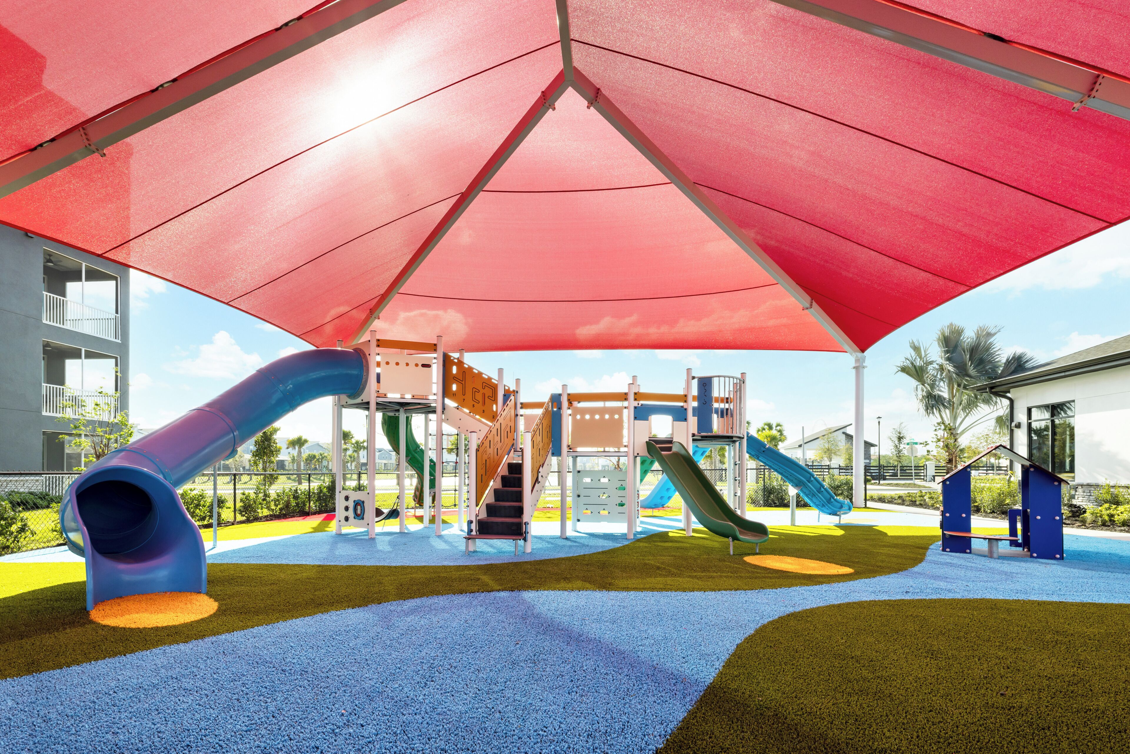 A playground with slides and climbing structures, surrounded by a covered area.