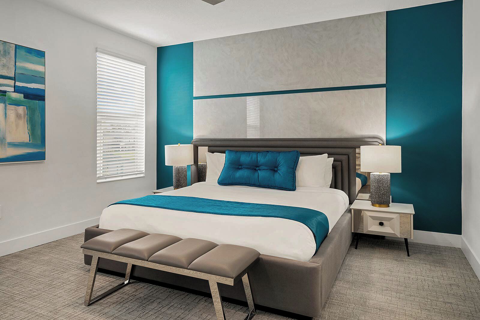 A modern bedroom with a large bed, two bedside tables, a bench, and a wall-mounted artwork.