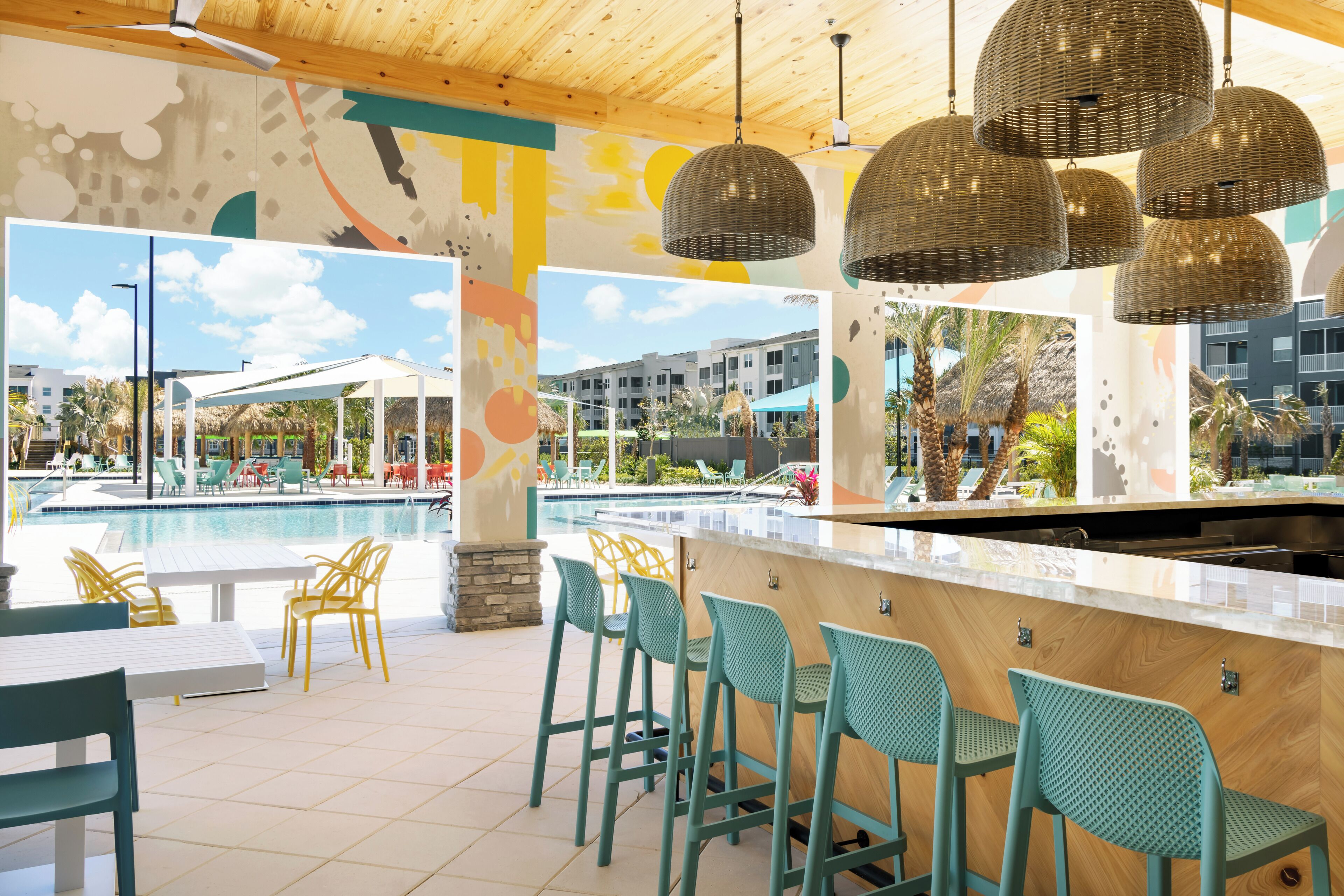 A poolside bar area with outdoor seating and a view of the pool and buildings in the background.