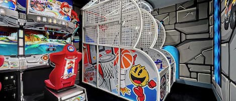 A gaming arcade with multiple Nintendo 64 consoles, a red Mario-themed machine, and a basketball-themed game.