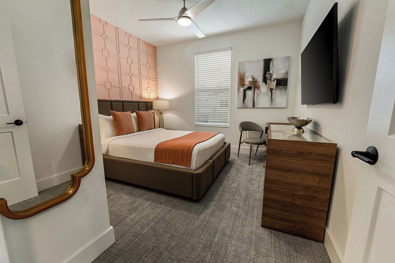 A bedroom with a bed, bedside table, chair, and artwork on the wall.