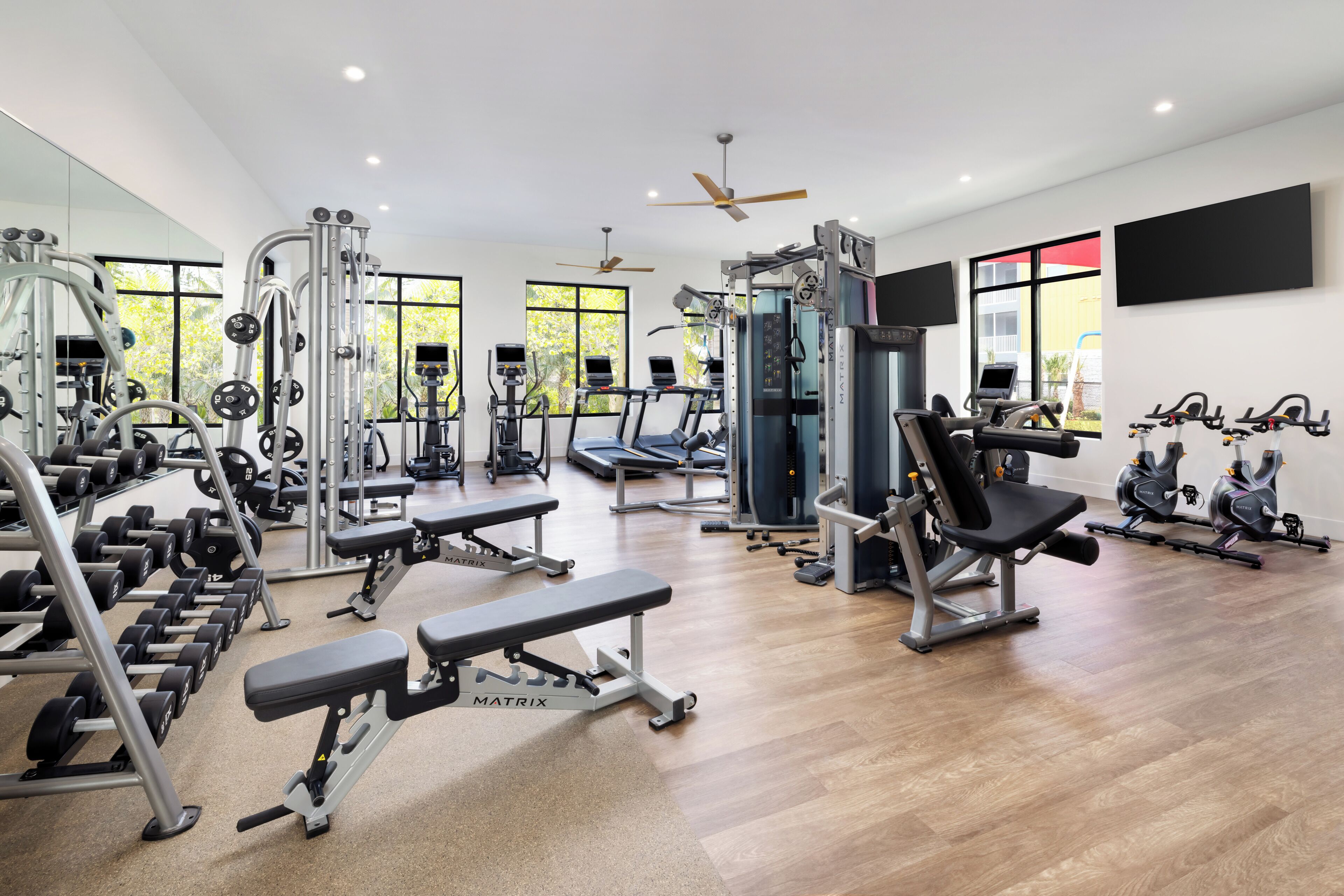 A gym with various exercise equipment, including treadmills, weight machines, and free weights.