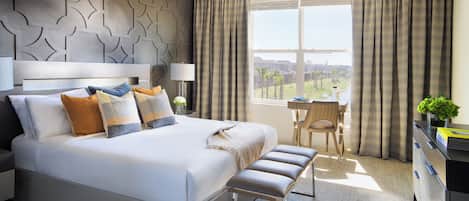 A modern hotel room with a large bed, a desk, and a view of the city.
