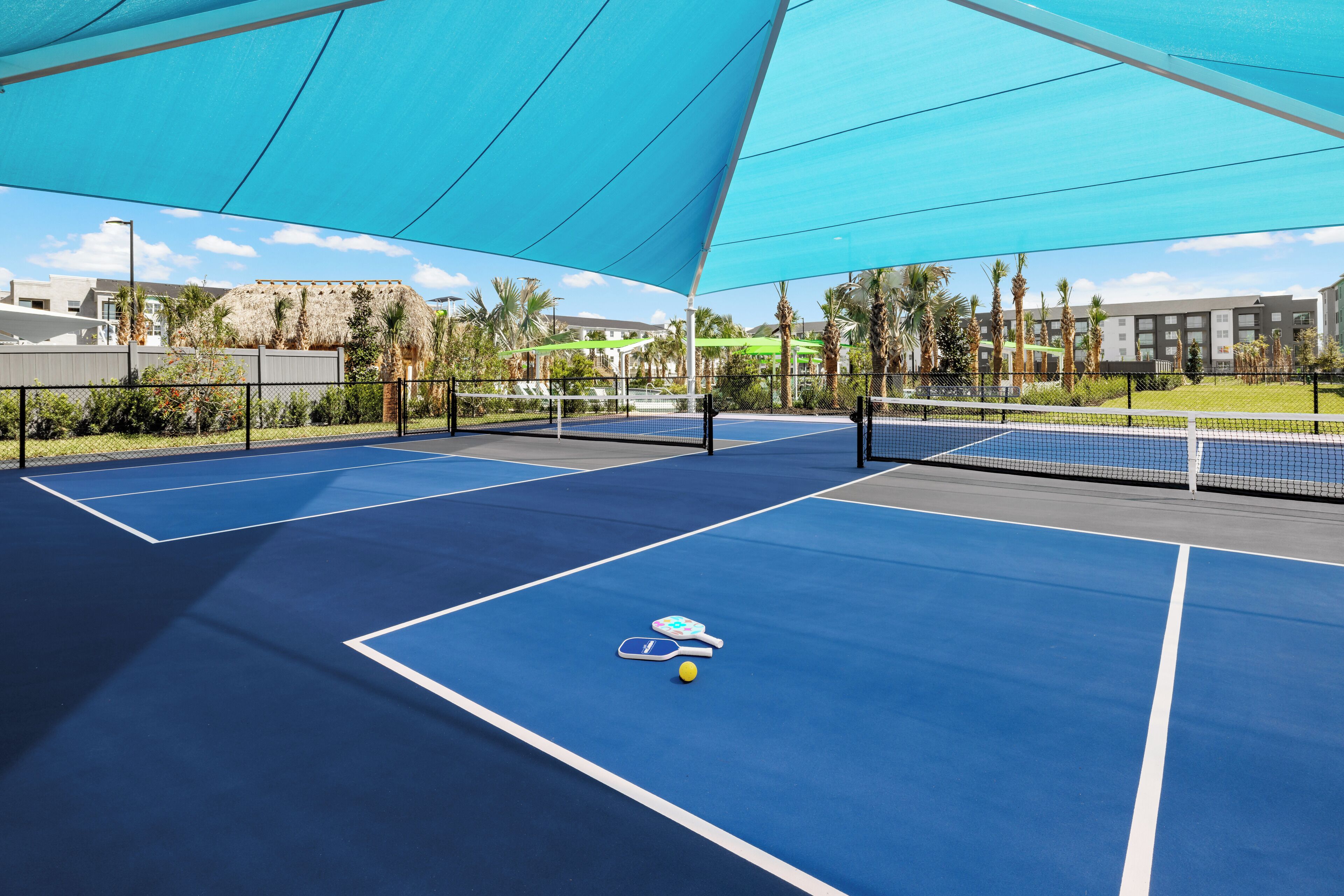 A tennis court with a net, two tennis rackets, and a ball.