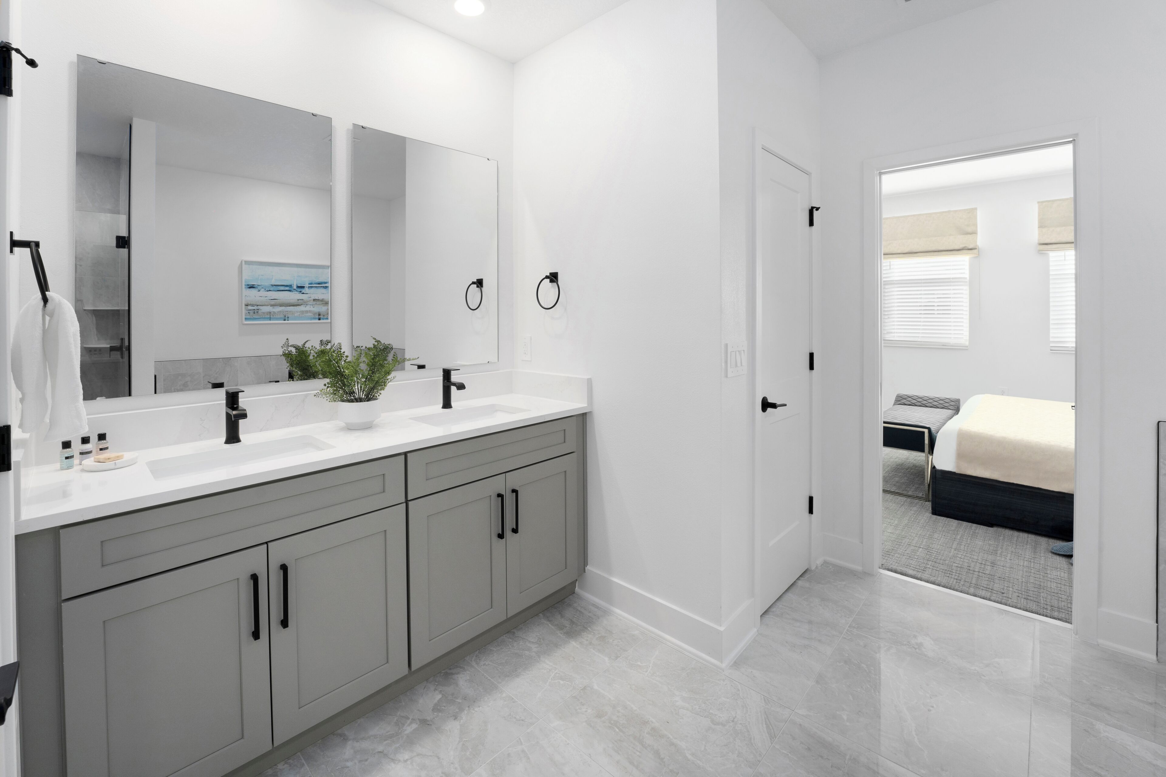 Une salle de bain moderne avec un grand miroir, deux lavabos et une plante en pot.