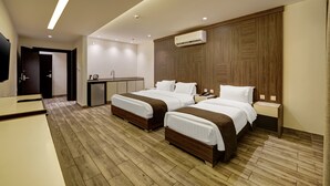 Een moderne hotelkamer met twee bedden, een bureau, een kleine kitchenette en een televisie.