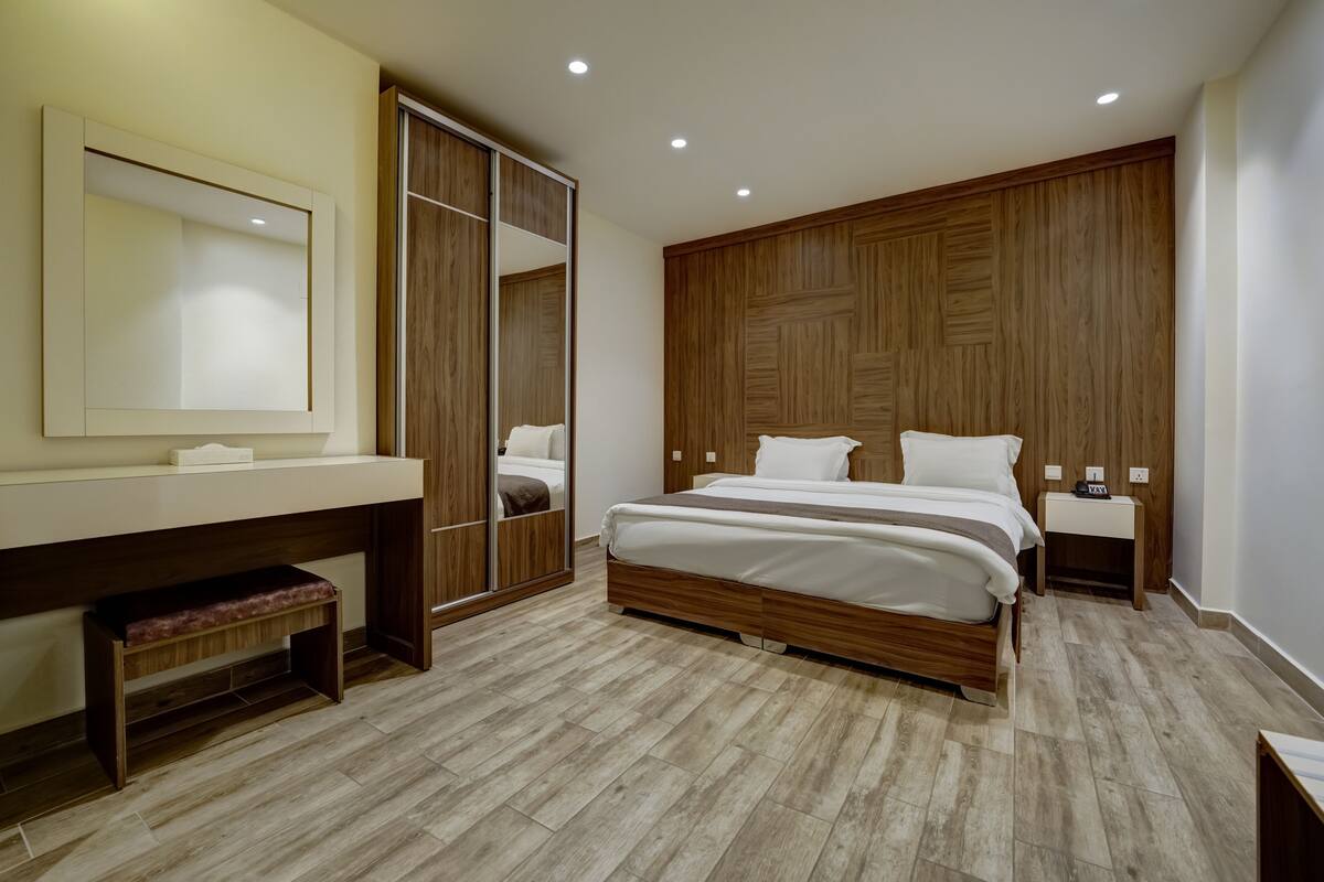 Une chambre moderne avec un lit en bois, un grand miroir, une armoire et une table de chevet.