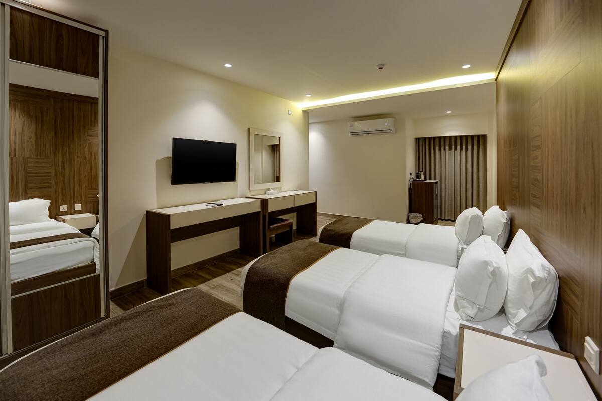 Une chambre d’hôtel avec deux lits, un bureau, une télévision et un appareil de climatisation.