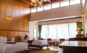 A hotel room with two beds, a dining table, and a chandelier.