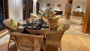Een eetruimte met rieten stoelen en een glazen tafel, gedekt voor een maaltijd.