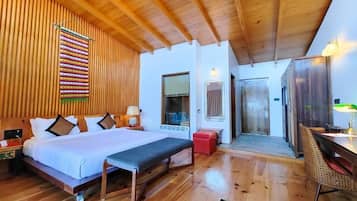 Quarto com piso de madeira, com cama, mesa de cabeceira, banco e área de refeições com mesa e cadeiras.