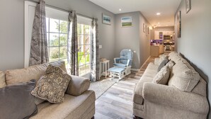A spacious living room with a sofa set, a blue armchair, and a view of the kitchen.